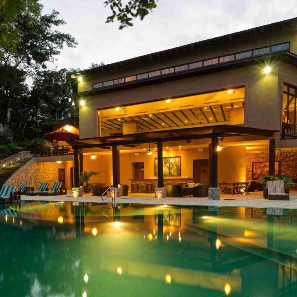 As the sun sets over Flores, Peten, Guatemala, a captivating view of Las Lagunas Boutique Hotel unfolds. The pool reflects the tranquil colors of dusk, framed by the elegant facade of the hotel. Warm lights from within create a cozy atmosphere, inviting guests to unwind and enjoy the serene beauty of this luxurious Guatemalan retreat.