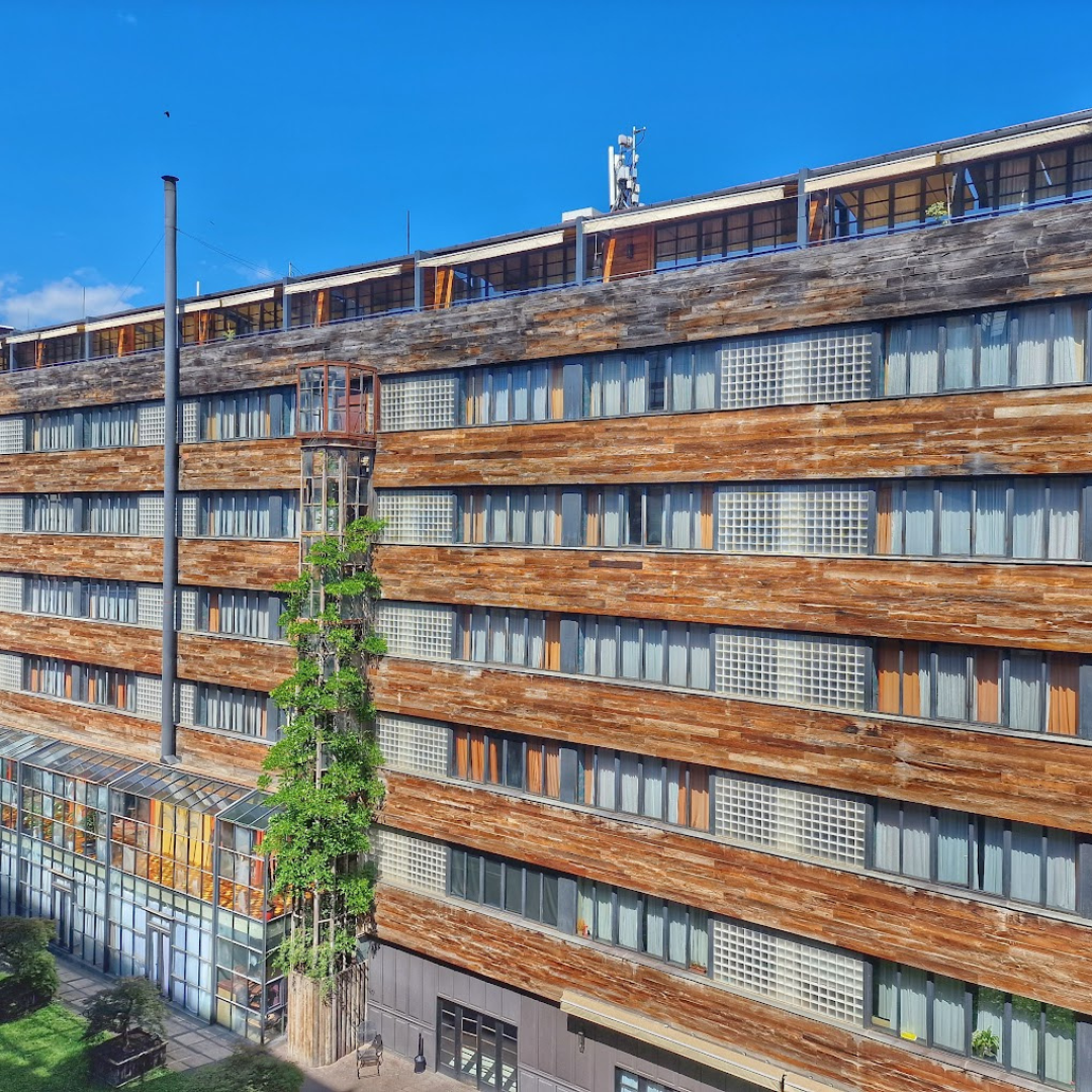 The outdoors facade of Stamba Hotel in Tbilisi, Georgia, showcasing its distinctive industrial design against a clear blue sky. The architectural charm of the building reflects modern sophistication, inviting guests to experience a unique blend of style and innovation in the heart of Tbilisi.