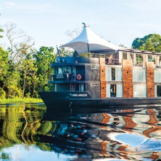 A captivating view of the M/V Amazon Aria gracefully cruising along the Amazon River in Peru, surrounded by lush rainforest and tranquil waters. A thrilling destination for self-flying pilots exploring South America