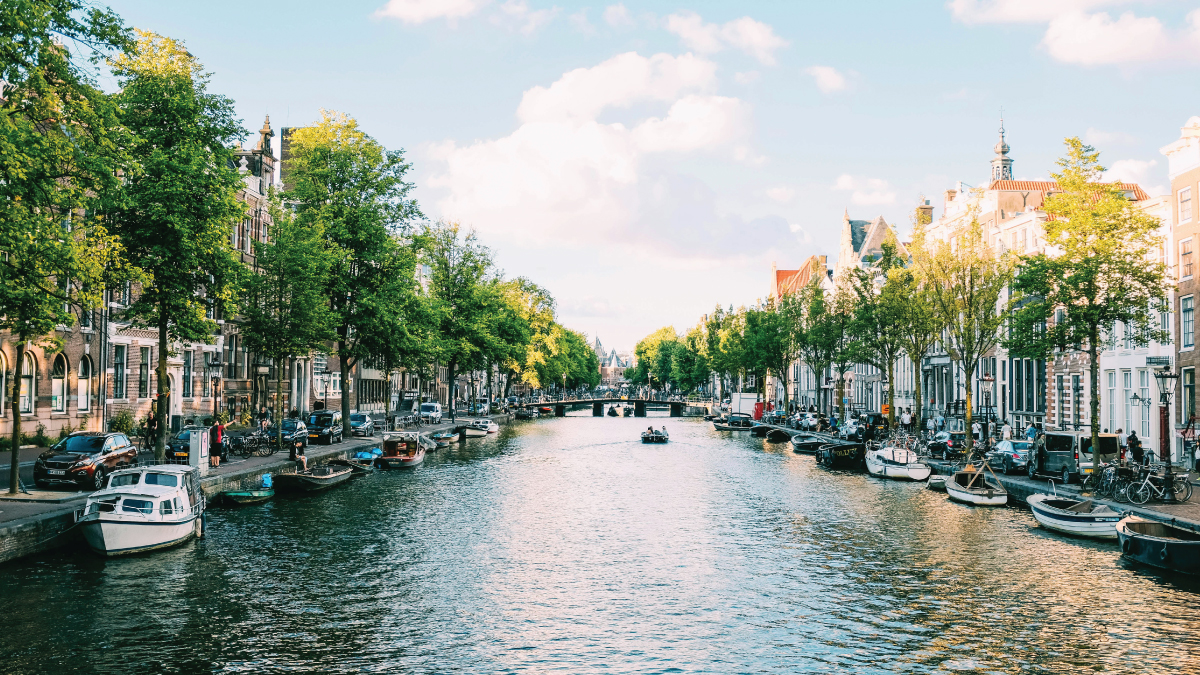 An enchanting view of the Prinsengracht Canal in Amsterdam, Netherlands, winding its way through historic neighborhoods lined with picturesque buildings. Ideal for self-flying pilots planning a European adventure