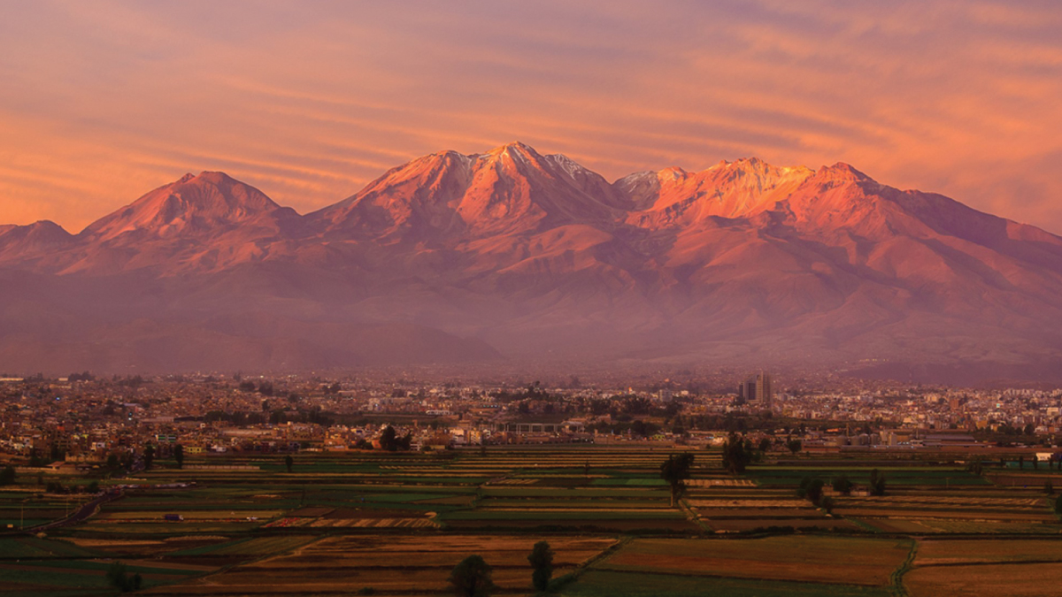 An enchanting aerial view of Arequipa, Peru, bathed in the warm hues of a red sunset, showcasing its historic architecture and picturesque landscapes. A captivating destination for self-flying pilots exploring South America