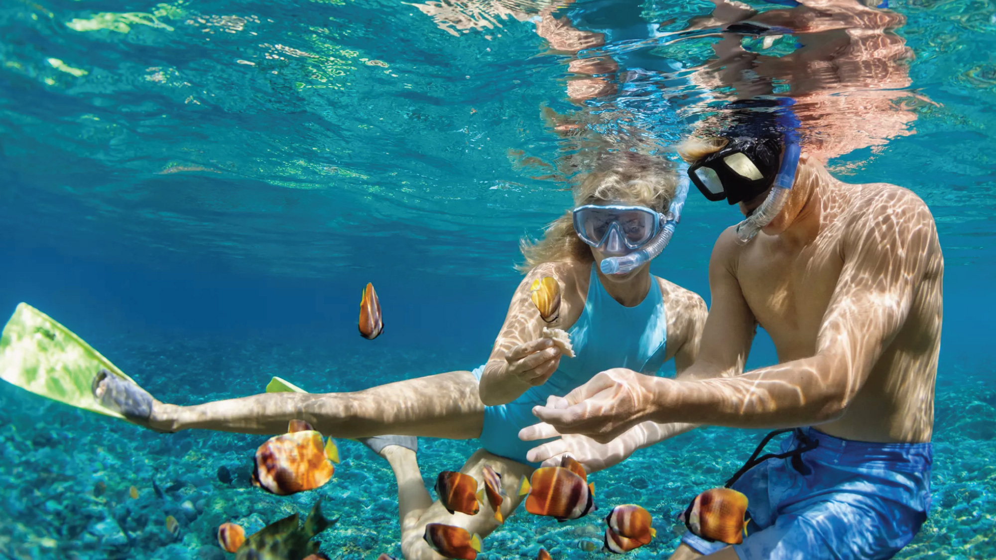 A couple snorkeling in the crystal-clear waters of Treasure Cay, Bahamas, a perfect destination for self-flying pilots looking to explore the pristine beauty of the Bahamas from land, sea, and air