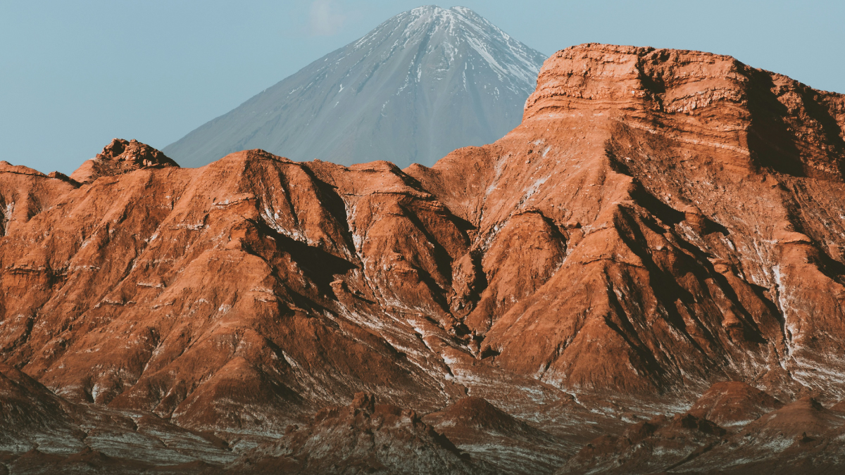 A captivating aerial view of the majestic mountains in the Atacama Desert of Chile, showcasing rugged peaks, deep valleys, and a stark yet mesmerizing landscape. A prime destination for self-flying pilots exploring South America