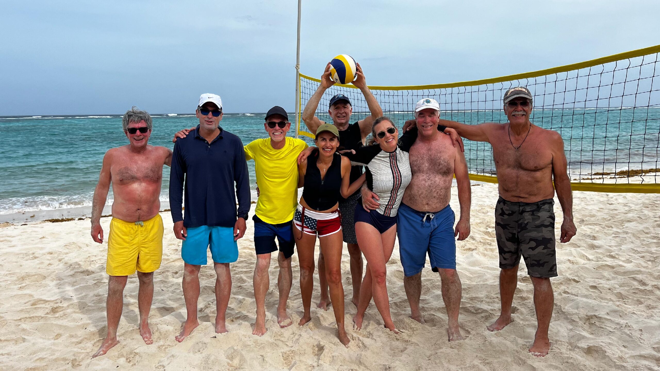 A group of travelers is playing beach volleyball on a sandy beach in Canouan, Grenadines.