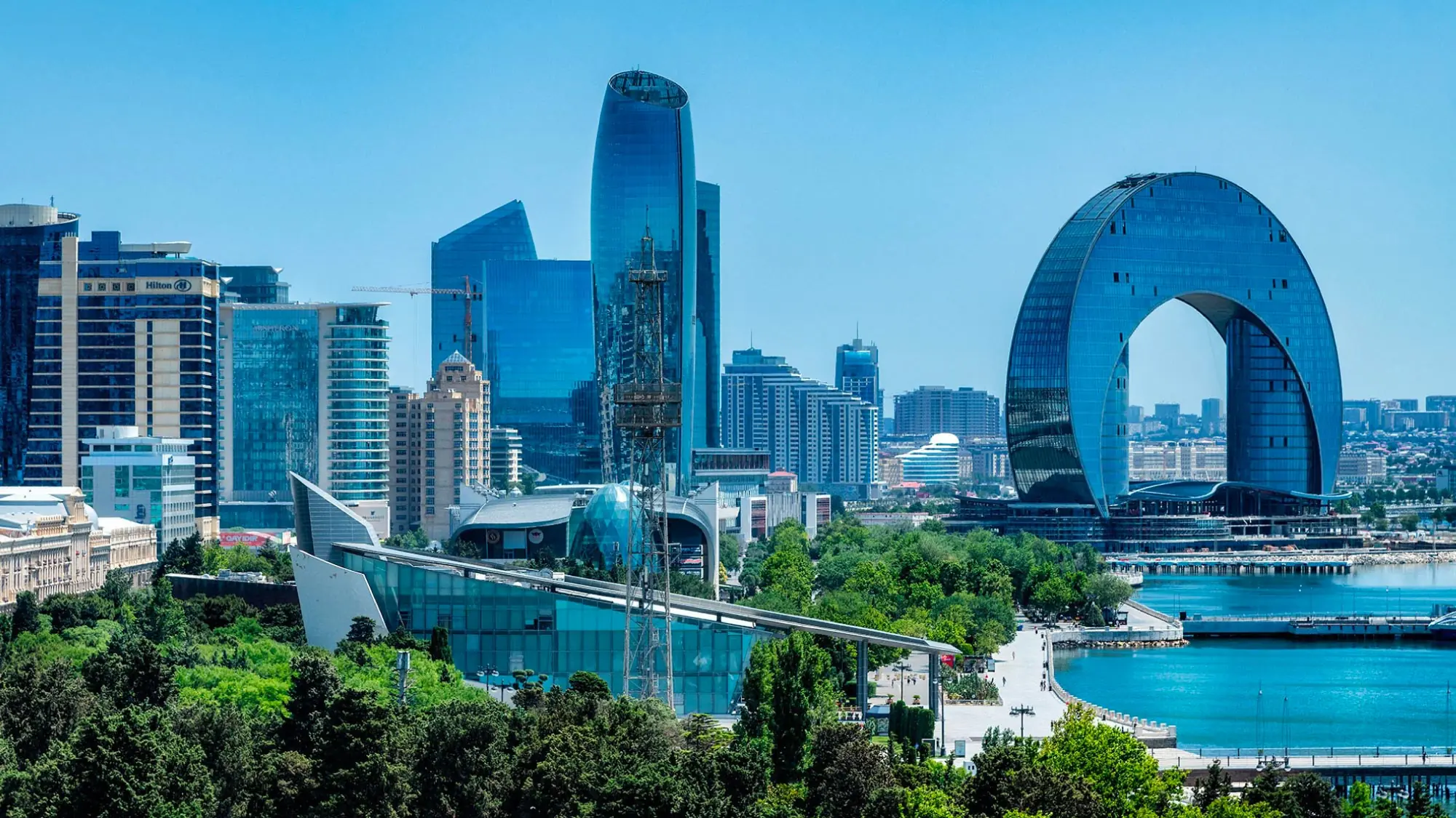 A picturesque view of the cityscape of Baku, Azerbaijan, featuring modern skyscrapers juxtaposed against historic buildings and the Caspian Sea. Baku is a highlight of a journey to Australia, visiting 21 countries, ideal for travelers who fly and own their own airplanes.