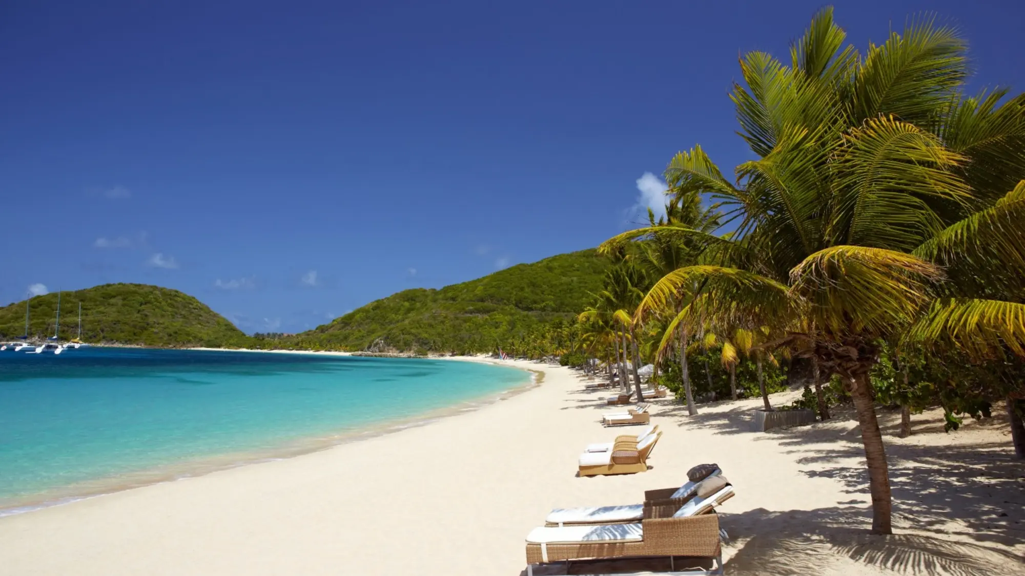 A serene image showcasing the sandy beach of Peter Island in the British Virgin Islands, washed by crystal-clear turquoise waters. Tailored for self-flying pilots planning a Caribbean adventure